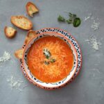 orange soup on white and blue ceramic bowl